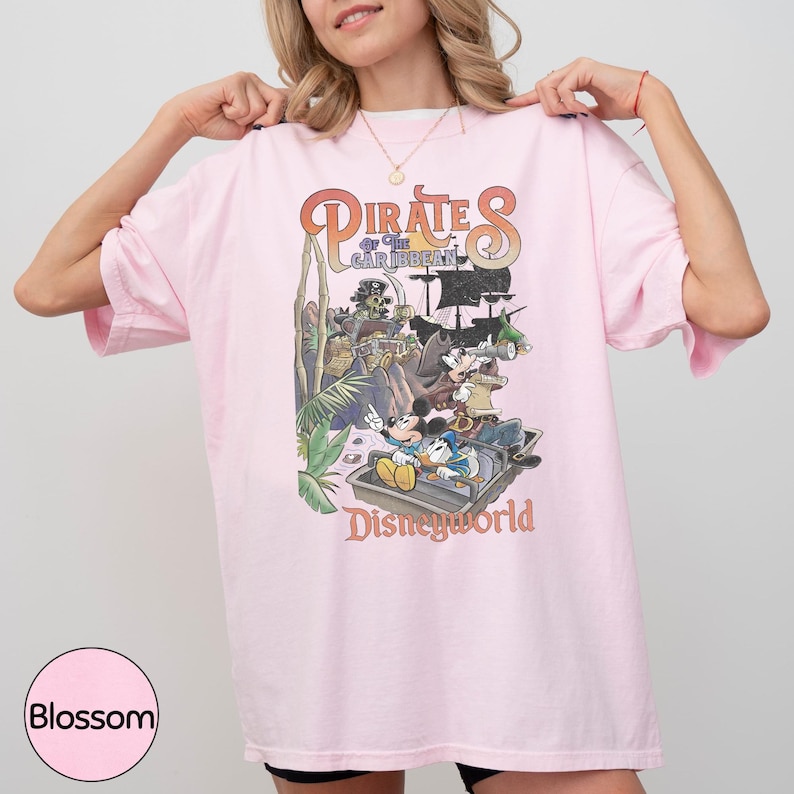 A woman wearing a pink t-shirt with a graphic of Disney characters from the Pirates of the Caribbean ride at Disneyworld.
