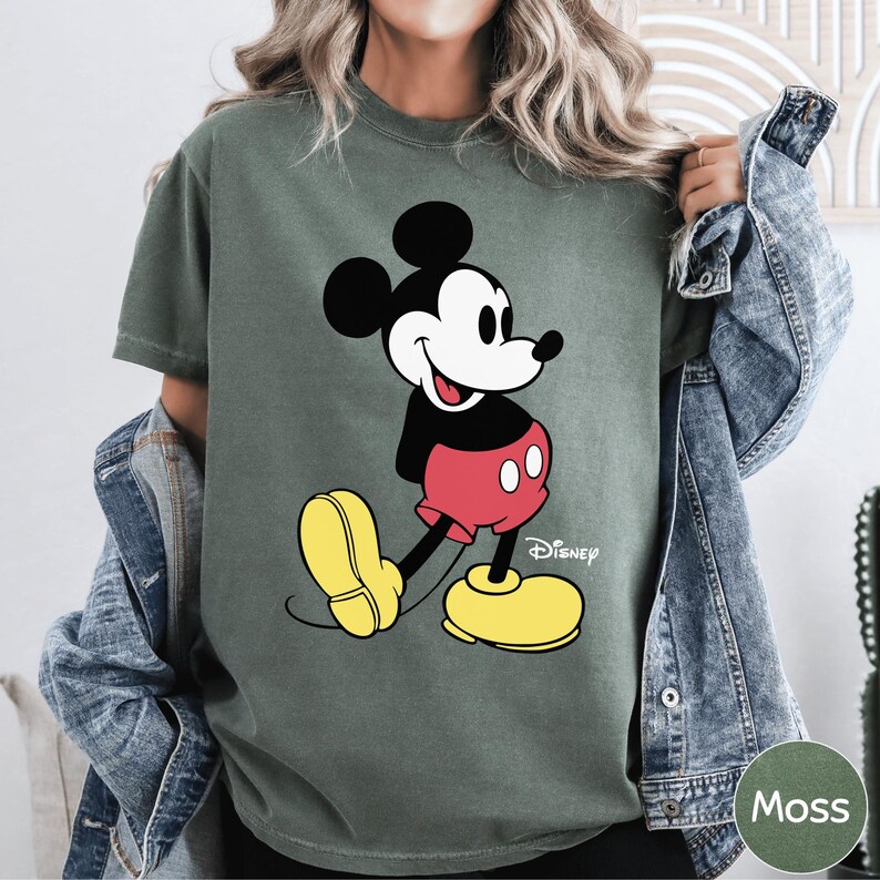 A woman wearing a green t-shirt with a cartoon image of Mickey Mouse and yellow shoes.