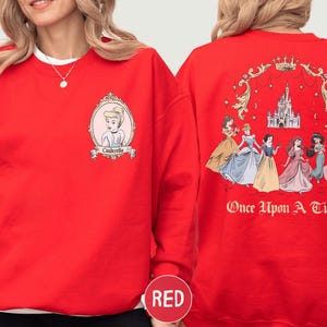A red sweatshirt with a design featuring the Disney princesses from "Cinderella" and the text "Once Upon a Time" on the back.