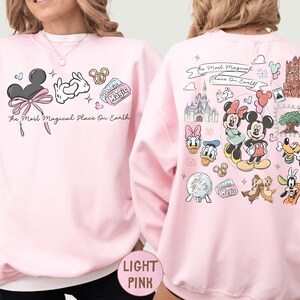 A woman wearing a pink sweatshirt with various Disney characters and Disney-themed graphics printed on it.