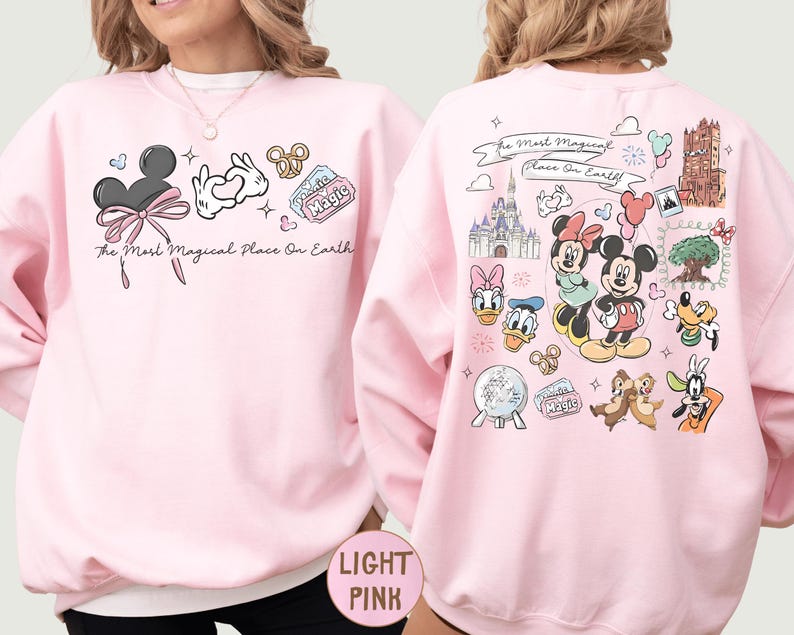 A woman wearing a pink sweatshirt with various Disney characters and Disney-themed graphics printed on it.