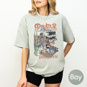 A woman wearing a t-shirt with a graphic of Disney characters and text related to the Pirates of the Caribbean ride at Disneyworld.
