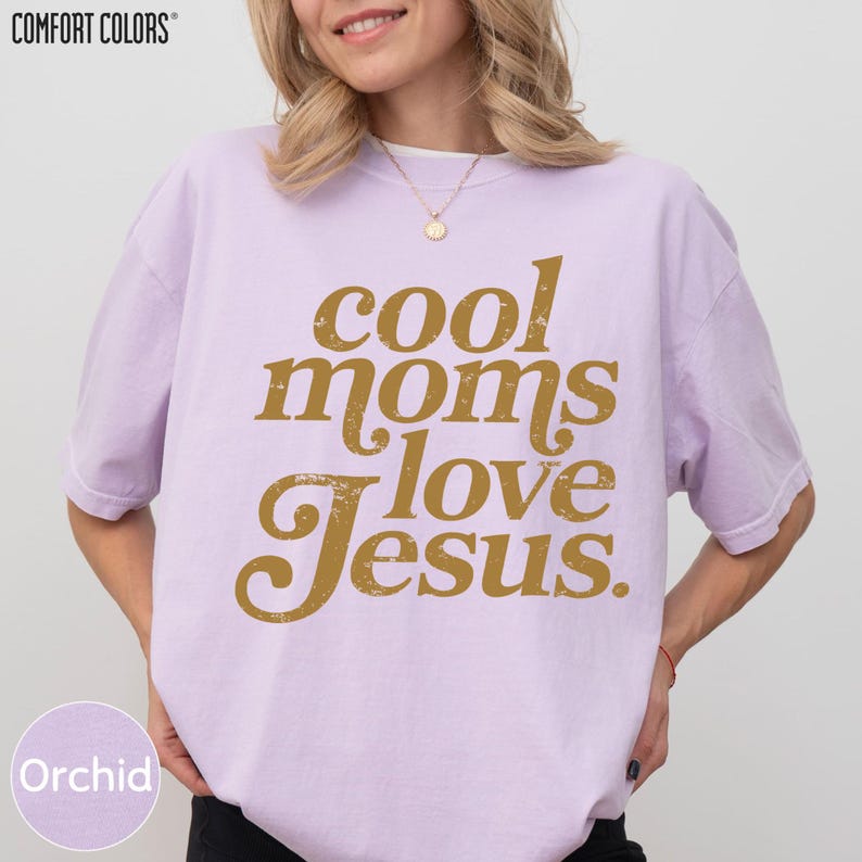 A woman wearing a pink t-shirt with the text "cool moms love Jesus" printed on it.