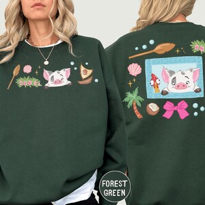 A woman wearing a green sweatshirt with a cartoon pig design and various other colorful elements.