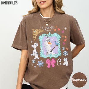 A woman wearing a brown t-shirt with a graphic design featuring characters from the Disney movie Frozen.