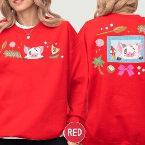 A red sweater with a cartoon pig design and various decorative elements, including a palm tree, seashells, starfish, and a bow.