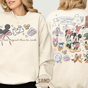 A woman wearing a white sweatshirt with various Disney characters and Disney-themed graphics printed on it.