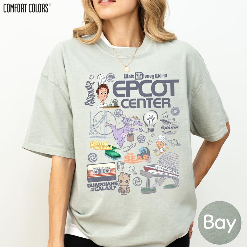 A woman wearing a gray t-shirt with various Disney-themed graphics and text, including characters, landmarks, and other iconic elements associated with the Walt Disney World Epcot Center.