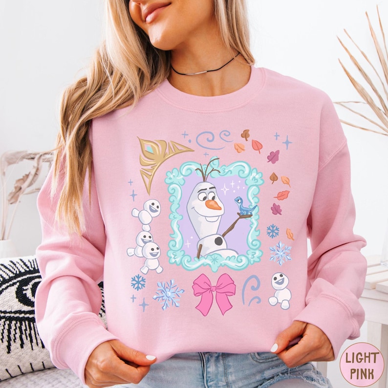 A woman wearing a pink sweatshirt with a graphic of Olaf from the Disney movie Frozen.