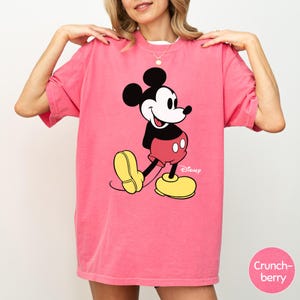 A woman wearing a pink t-shirt with a cartoon character printed on it.