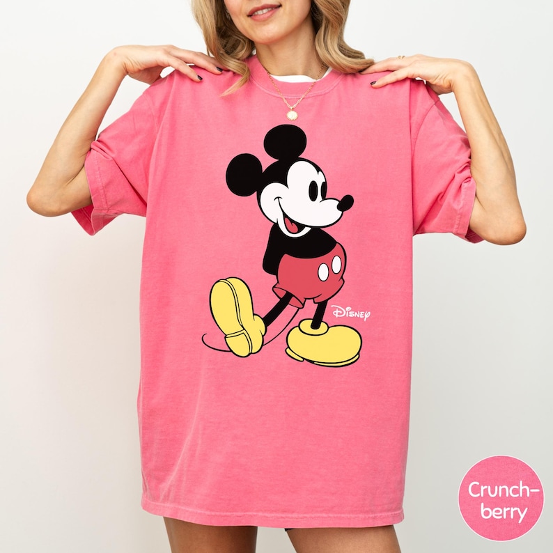 A woman wearing a pink t-shirt with a cartoon character printed on it.
