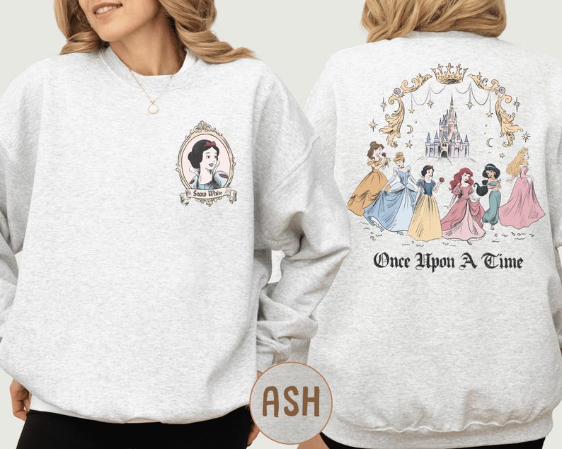A woman wearing a grey sweatshirt with a design featuring the characters from the Disney film "Once Upon a Time".