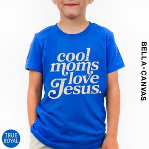 A young boy wearing a blue t-shirt with the text "cool moms love Jesus" printed on it.