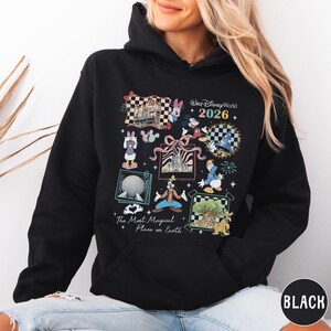 A woman wearing a black hoodie with a colorful graphic design featuring various Disney characters and landmarks.