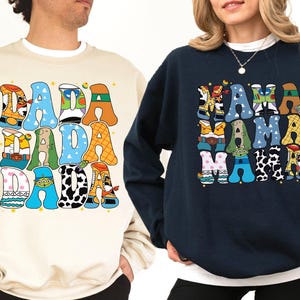 two people wearing sweatshirts with colorful text and graphics.