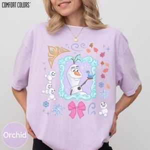 A woman wearing a pink t-shirt with a graphic design featuring characters from the Disney movie Frozen.