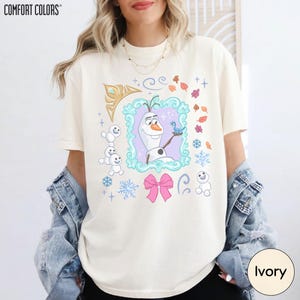 A woman wearing a white t-shirt with a graphic design featuring characters from the Disney movie Frozen.