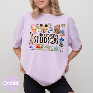 A woman wearing a pink t-shirt with various Disney and Hollywood-themed graphics and text, including Mickey Mouse, the Star Wars logo, and other iconic symbols.