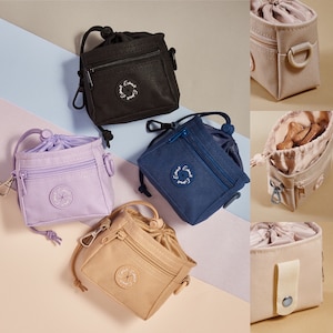 May include: Five different dog treat pouches in various colors, including black, purple, blue, beige, and pink. Each pouch has a zipper closure and a small strap with a metal clip. The pouches have a circular logo with the text "Everest Pet" on them.
