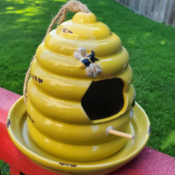 Beehive Birdhouse will add a peppy touch to your outdoor decor.  Designed like a beehive and sporting a yellow shade with a print of bees.