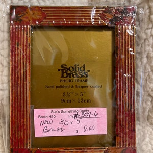 Könnte beinhalten: Ein roter und goldener Bilderrahmen aus massivem Messing. Der Rahmen ist 9 cm x 13 cm groß und handpoliert und lackiert. Der Rahmen ist neu und kostet 8,00 €.