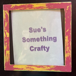 Könnte beinhalten: Ein rosa-goldener Bilderrahmen mit dem Text "Sue's Something Crafty" auf weißem Hintergrund.