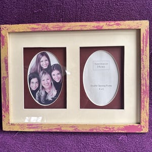 Könnte beinhalten: Ein Bilderrahmen mit zwei Öffnungen in einem abgewetzten Rosa- und Goldton. Der Rahmen ist von Sheffield Home und für zwei Fotos im Format 10x15 cm ausgelegt.