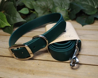 May include: A dark green rubber dog collar and leash set with silver hardware. The collar has a buckle closure and the leash has a hook.