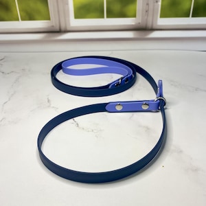 May include: A blue and purple dog leash with silver hardware. The leash is made of a durable, rubber-like material.