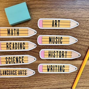 May include: Seven yellow pencil-shaped labels with pink eraser ends. Each label has a different subject written in black text: Math, Reading, Science, Language Arts, Art, Music, History, and Writing.