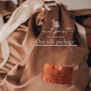 May include: A brown silk pouch with a white label that says "wool.point knitwear boutique" and the text "Our silk package".