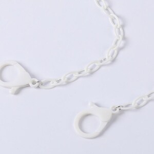 May include: White plastic chain with two white plastic clasps. The chain is a simple oval link style.