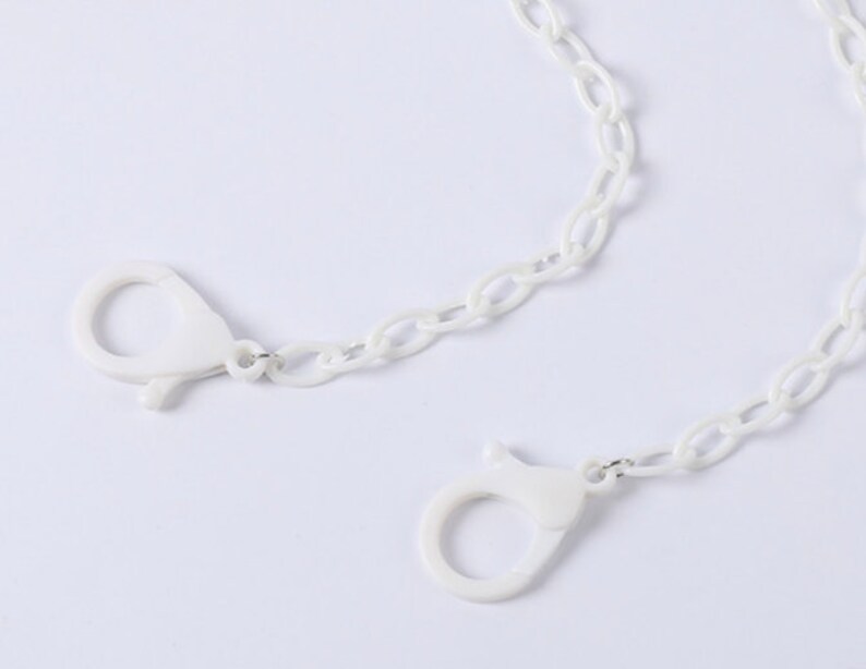 May include: White plastic chain with two white plastic clasps. The chain is a simple oval link style.
