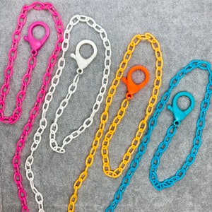 May include: Four colorful chain necklaces with different colored clasps. The chains are pink, white, orange, and blue.