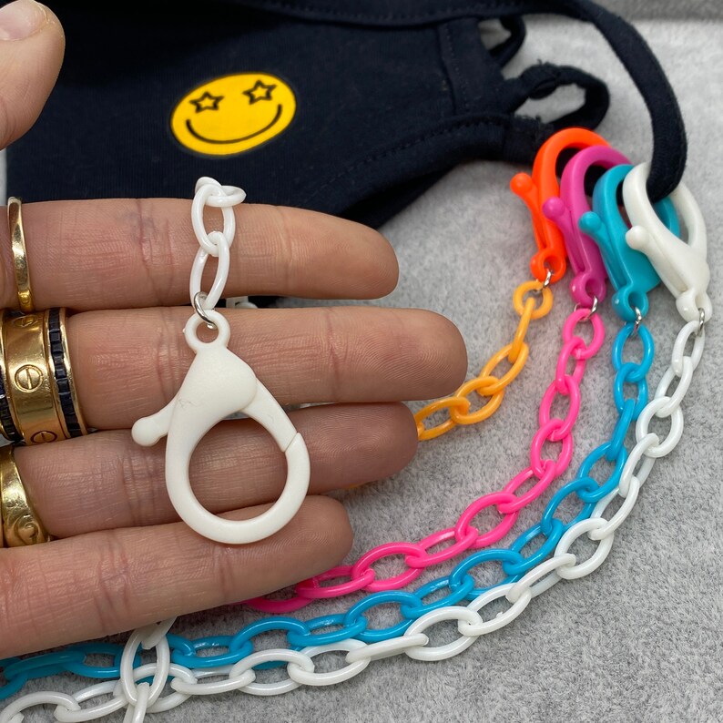 May include: A set of colorful plastic chains with white clasps. The chains are in shades of blue, pink, orange, and white. The chains are designed to be used as a mask lanyard.