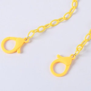 May include: A yellow plastic chain with two yellow plastic clasps. The chain is made of oval links.