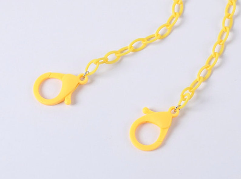 May include: A yellow plastic chain with two yellow plastic clasps. The chain is made of oval links.