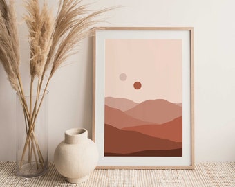 Può includere: Una stampa artistica incorniciata con un paesaggio minimalista con montagne a strati nei toni del marrone e del rosso. Due corpi celesti sono raffigurati nel cielo. L'opera d'arte è esposta con erba della pampa essiccata e un vaso di ceramica bianco.