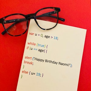 May include: A white card with code written on it in different colors. The code is a JavaScript function that checks if a person is of age. The code is written in a simple font and is easy to read. The card is on a red background.