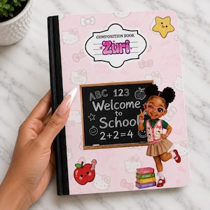 May include: A light pink composition book with a black spine featuring a Hello Kitty pattern. The cover displays a label reading Composition Book Zuri, a chalkboard graphic with the text Welcome to School ABC 123 2+2=4, a yellow star, and an apple.