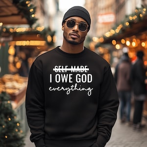 May include: Black sweatshirt with white text that reads "SELF MADE I OWE GOD everything".