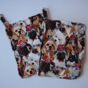 May include: Two white quilted pot holders with a red, white, and blue patriotic dog print. The dogs are wearing red, white, and blue hats.