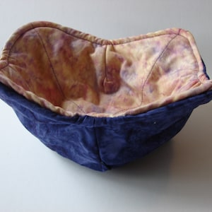 Könnte beinhalten: Eine blaue Stoffschale mit einer gelben und rosa gemusterten Auskleidung. Die Schale ist aus weichem, gestepptem Stoff gefertigt und eignet sich perfekt zum Aufbewahren von Kleinigkeiten.