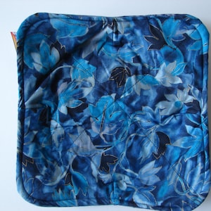 May include: Blue quilted hot pad with a floral pattern. The pattern features blue, teal, and silver leaves on a dark blue background.