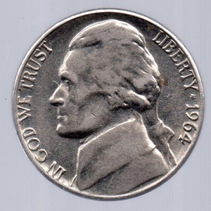 May include: A silver US nickel coin with the profile of Thomas Jefferson on the obverse. The coin has the inscription "IN GOD WE TRUST" and "LIBERTY 1964".