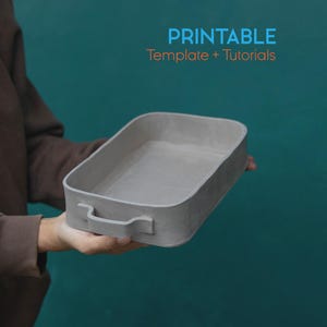 Puede incluir: Una bandeja rectangular gris con asas se sostiene sobre un fondo turquesa. La bandeja tiene un interior liso y un exterior texturizado. El texto "PRINTABLE Template + Tutorials" está en la esquina superior derecha.