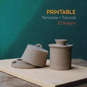 Op de afbeelding: Twee beige keramische botervlootjes met deksels en een klein bordje worden gepresenteerd op een houten snijplank. De tekst "PRINTABLE Template + Tutorials 2 Designs" staat op de achtergrond.