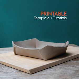 May include: A handmade, light-coloured clay bowl with a unique folded design, resting on a wooden chopping board. The text "PRINTABLE Template + Tutorials" is displayed in orange. The background is a teal colour.
