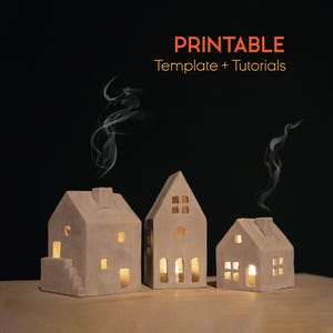 Puede incluir: Tres candelabros de cerámica beige con forma de casa con velas encendidas en su interior, que emiten un brillo cálido. Volutas de humo se elevan de las chimeneas. El texto "PRINTABLE Template + Tutorials" se muestra en naranja.