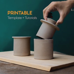May include: Three beige ceramic butter dishes, one with the lid being lifted. The text "PRINTABLE Template + Tutorials" is in the upper left corner. The dishes are on a wooden board against a teal background.